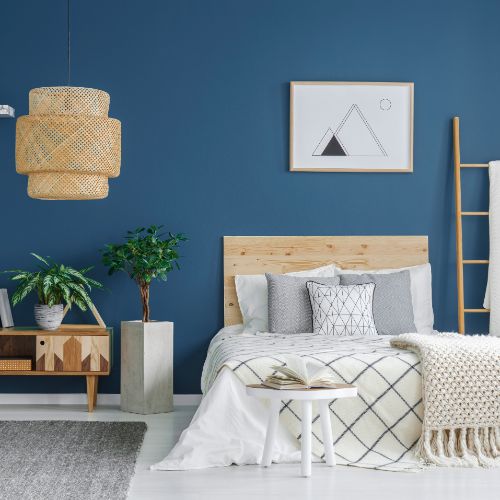 blue bedroom wall with neutral furniture