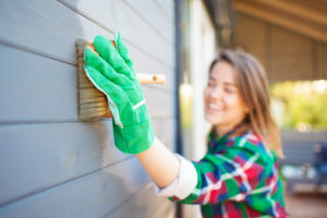Woman painting exterior vinyl home
