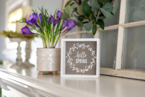 Hello spring sign with purple flowers on the mantel